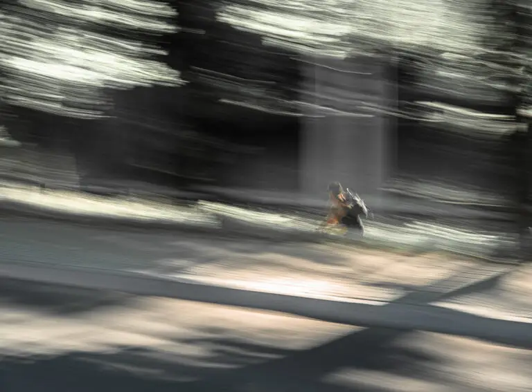 W ruchu. Rowerzysta w mieście oświetlony przez słońce. Obraz rozmyty w wyniku zamierzonego ruchu kamery.